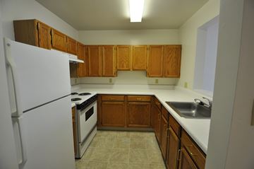 Baltimore apartment for rent - a kitchen with white appliances and wooden cabinets and a refrigerator