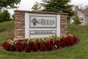 Catonsville apartment for rent - A sign for The Greens at Rolling Road stands in front of a house.