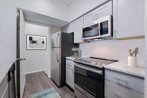 St. Petersburg apartment for rent - a kitchen with white cabinets and black appliances and a refrigerator at Promenade at Carillon, St. Petersburg, FL, 33716