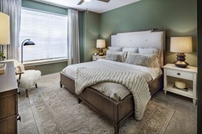 Flowery Branch apartment for rent - A bedroom with a large bed and a white chair at Folksong Apartments, Flowery Branch