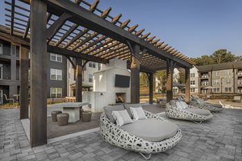 A wooden pergola over a patio with white cushioned seating