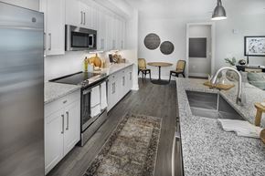 Flowery Branch apartment for rent - A modern kitchen with a refrigerator on the left and a dining area in the middle at Folksong Apartments, Flowery Branch, Georgia