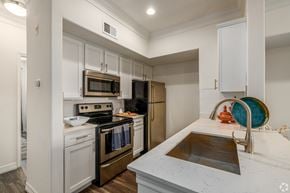 Round Rock townhouse for rent - A kitchen with white cabinets and a marble countertop.