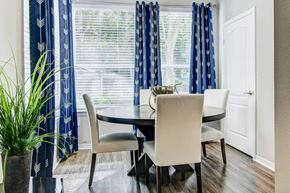 Tampa apartment for rent - Separate dining area with large windows, window coverings, and a circular wooden table with four cream chairs at Tuscany Bay Apartments, Florida