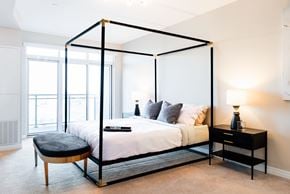 London apartment for rent - A bedroom with a four poster bed and a bench.