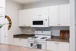 London apartment for rent - A white kitchen with a microwave oven and a stove.