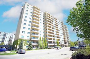 London apartment for rent - A large white apartment building with balconies and a parking lot in front.