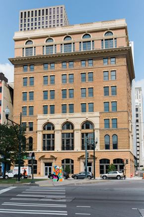 New Orleans apartment for rent - A large, old building with many windows sits on a city street corner.