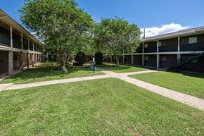 Lafayette apartment for rent - A grassy courtyard with trees and apartment buildings in the background.