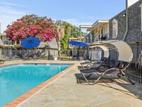 Lafayette apartment for rent - A pool surrounded by chairs and umbrellas with a building in the background.