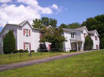 Meadville apartment for rent - a white house with red shutters and a grassy yard