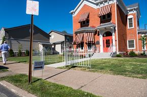 Erie apartment for rent - a man walking past a house with a sign in front of it
