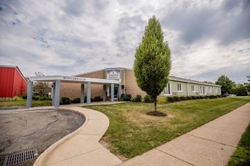 Erie apartment for rent - the front of a brick building with a sidewalk and a tree