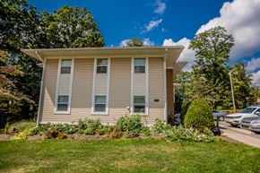 Meadville apartment for rent - a tan house with a lawn in front of a parking lot