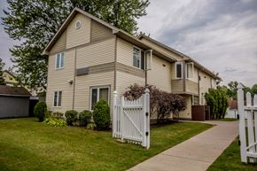 Erie apartment for rent - a yellow house with a white fence and a sidewalk