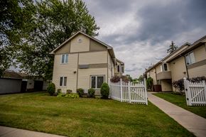 Erie apartment for rent - a house with a white picket fence in front of a green yard