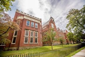 Erie apartment for rent - a large brick building with a green lawn and a fence