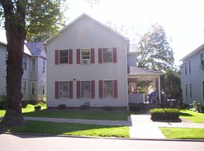 Meadville apartment for rent - a white house with red shutters and a sidewalk in front of it