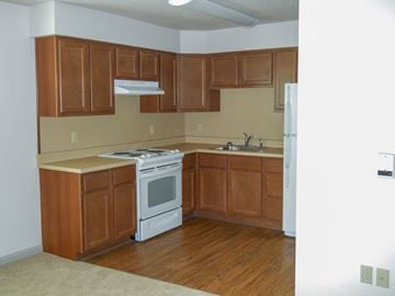 Erie apartment for rent - an empty kitchen with wooden cabinets and a white stove and refrigerator