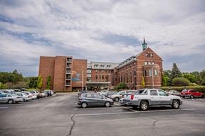 Erie apartment for rent - a parking lot filled with cars in front of a brick building