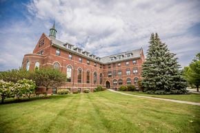 Erie apartment for rent - a large brick building with a lawn and a tree