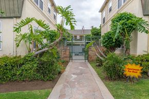 Los Angeles apartment for rent - a walkway between two apartment buildings with a fence and palm trees