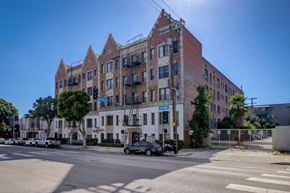 Los Angeles apartment for rent - A large brick building with a white section in the middle is situated on a street corner.
