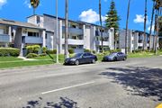 Reseda apartment for rent - Two cars are parked on the side of a street in front of apartment buildings.