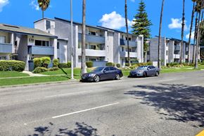Reseda apartment for rent - Two cars are parked on the side of a street in front of apartment buildings.