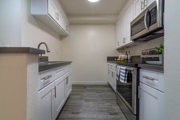 Los Angeles apartment for rent - A kitchen with white cabinets and a black stove top oven.