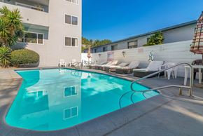 Los Angeles apartment for rent - A swimming pool in front of a building with sun loungers.