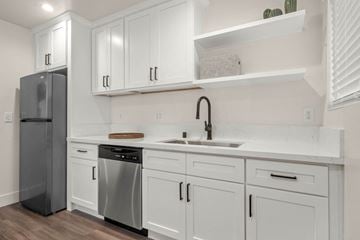 Covina apartment for rent - A kitchen with white cabinets and a black refrigerator.