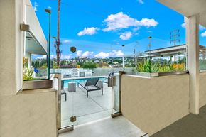 Los Angeles apartment for rent - A balcony with a glass door and a bench overlooking a pool.