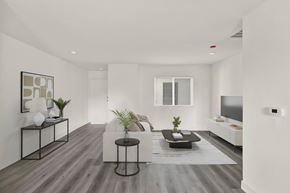 Los Angeles apartment for rent - A modern living room with a white couch, a black coffee table, and a TV on the wall.