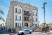Los Angeles apartment for rent - A white car is parked in front of a two-story building with a balcony.