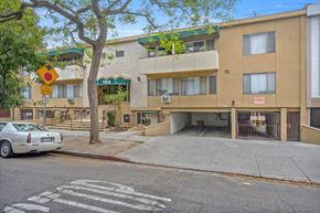 West Hollywood apartment for rent - A street view of a building with a car parked in front.