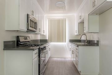 West Hollywood apartment for rent - A kitchen with white cabinets and a black countertop.