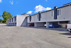 Reseda apartment for rent - A parking lot with a blue car parked in front of a building.