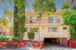 West Hollywood apartment for rent - A building with a red fence and a tree in front of it.