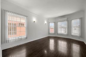 Los Angeles apartment for rent - A room with wooden floors and three windows with blinds.