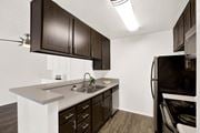Canyon Country apartment for rent - a kitchen with dark wood cabinets and white counter top and a black refrigerator at Monterra Ridge Apartments, Canyon Country ,91351