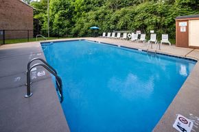 Winston Salem apartment for rent - A pool with a blue tinted water and white chairs around it.