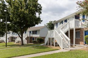 Greensboro apartment for rent - A white two-story house with a balcony and stairs leading to the second floor.