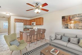 Hope Mills apartment for rent - A living room with a grey couch, a green chair, and a brown bar stool.