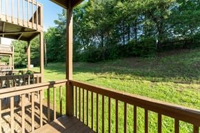 Winston Salem apartment for rent - A wooden deck overlooks a grassy field and trees.