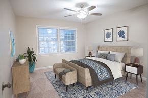 Fayetteville apartment for rent - A bedroom with a large bed, a chair, and a ceiling fan.