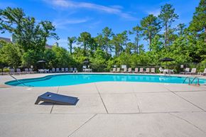 Wilmington apartment for rent - A large outdoor swimming pool surrounded by trees and lounge chairs.