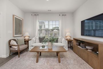Whitsett apartment for rent - A living room with a white couch, a wooden coffee table, and a painting on the wall.