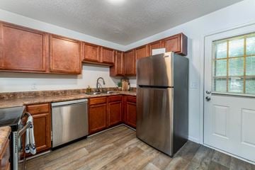 Winston Salem apartment for rent - A kitchen with wooden cabinets and a stainless steel refrigerator.