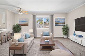 Fayetteville apartment for rent - A living room with a white couch, a coffee table, a ceiling fan, and two potted plants.